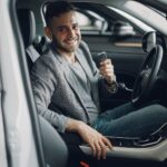Traveler holding car keys standing beside rental vehicle ready for road trip
