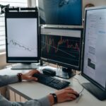 Professional trader analyzing charts on multiple monitors in modern office environment