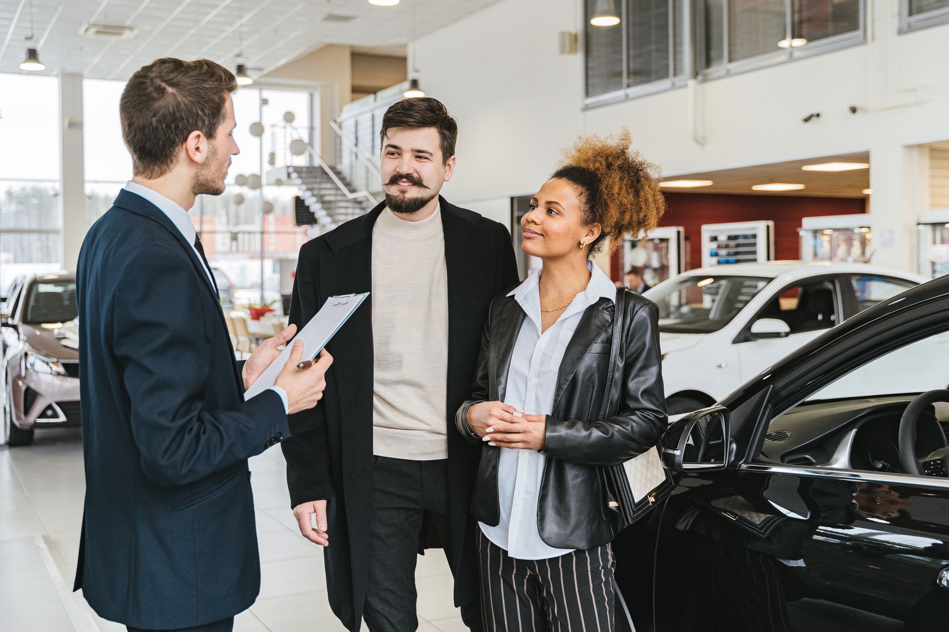 person signing car rental agreement with keys and vehicle in background
