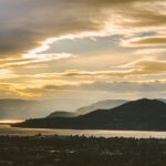 Landscape view of mountains and a lake under a cloudy sky during sunset
