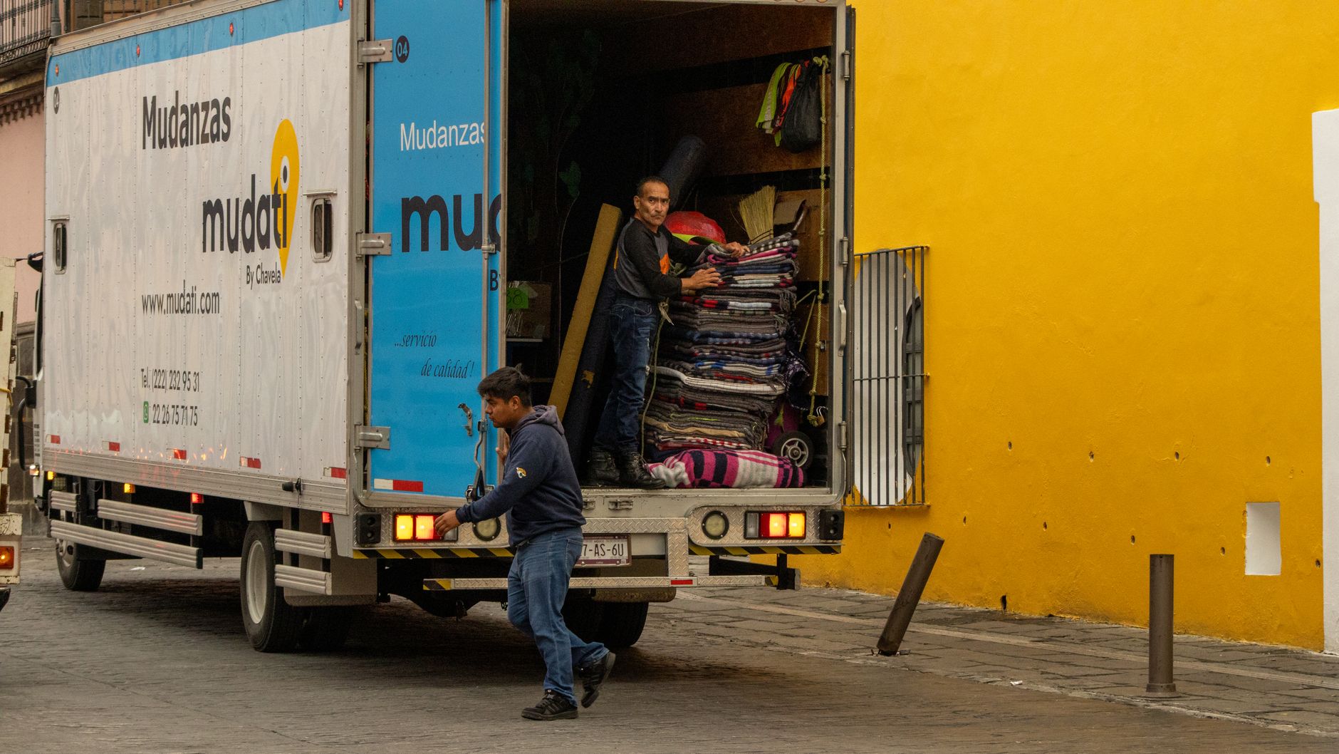 Professional moving company workers safely loading household items into moving truck