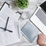 Person reviewing healthcare insurance plans on tablet with documents